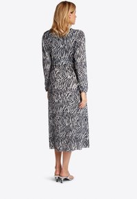 Langärmliges Maxikleid im Schwarz-Weiß-Zebra-Print, mit einer taillierten Taille und einem fließenden Rock. Weicher Stoff mit glatter Textur.