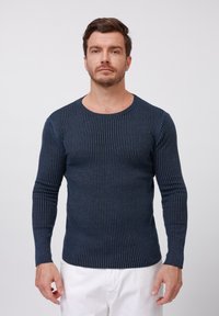 Navy blue ribbed long-sleeve sweater with a round neckline, featuring a fitted design and textured fabric. Light and soft material.