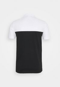 Polo tričko s krátkým rukávem, které má design s barevnými bloky - bílá horní polovina a černá dolní polovina, vyrobené z měkké bavlny.