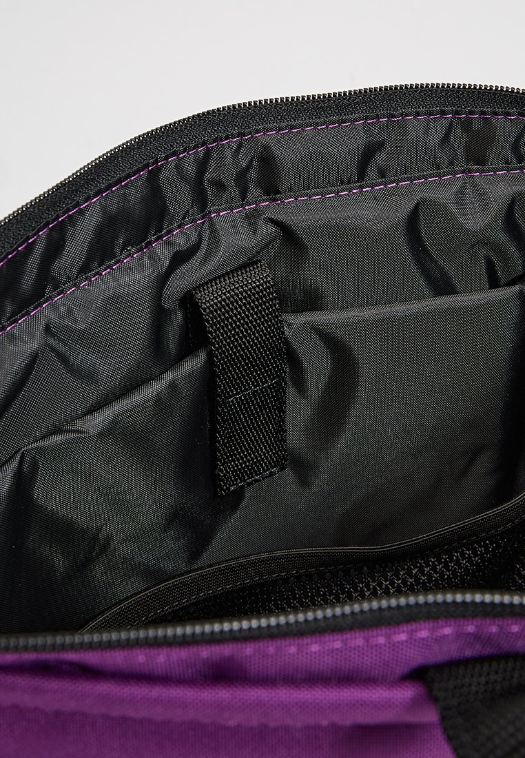 Interno di borsa viola con una fodera nera liscia, dotato di una tasca laterale e una chiusura con cerniera. Cucito con accenti di filo nero e viola.