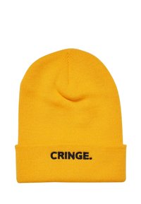 Kollane kudum beanie, millel on äär, ja ees on musta tikandiga sõna "CRINGE.". Tekstuur on pehme ja veniv.