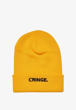 Žlutá pletená čepice s  nákrčníkem, na přední straně s černou výšivkou slova "CRINGE." Textura je měkká a pružná.