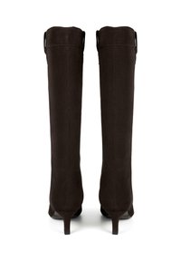 Un paio di stivali alti in suede marrone scuro con tacco sottile, visti da dietro su uno sfondo bianco.
