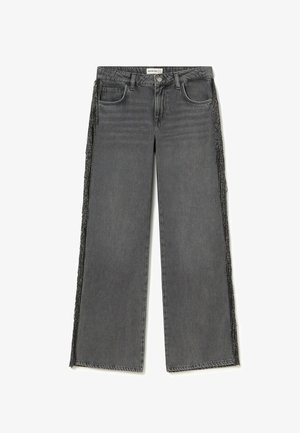 Jeans grises de tiro alto y pierna ancha con trabillas para cinturón, bolsillos delanteros y traseros, cierre de botón y ribete negro con flecos a lo largo de las costuras exteriores laterales.