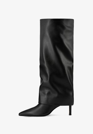 Botines de cuero negro con un empeine suave y caído, punta afilada y tacón de stiletto delgado. El acabado texturizado añade interés visual.