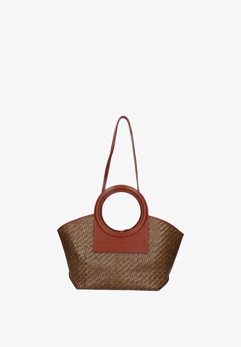 Woven straw tote bag with a brown leather circular handle and rectangular base, featuring a solid leather accent on one side.