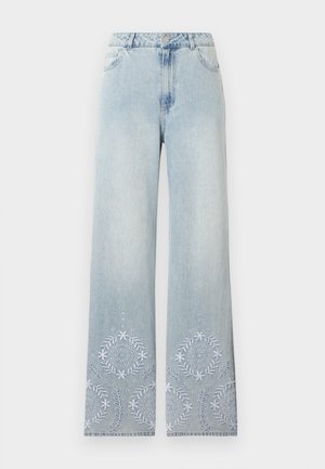 Jean pattes larges bleu clair avec fermeture à boutons et broderie florale blanche au bas des deux jambes.