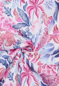 Tessuto di cotone caratterizzato da un vortice di motivi floreali in rosa, viola e blu su uno sfondo bianco, che mette in mostra una texture morbida e colori vivaci.