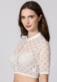 Weiße, aus Spitze gefertigte, kurzärmelige Bluse mit diamantartigem Muster, Kragen und cropped Schnitt. Sie verfügt über einen gewellten Saum und einen Knopfverschluss.