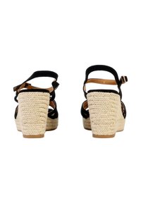 Sandali con zeppa in espadrilla nera, design con cinturini, tacco in juta testurizzato e cinturino alla caviglia regolabile, che mostrano una finitura intrecciata naturale.