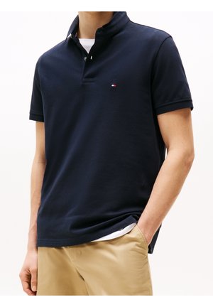 Polo bleu marine en coton, doté d'un col, de manches courtes et d'un petit logo sur la poitrine. Texture lisse, coupe classique.