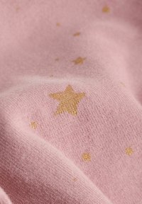 Pink fabric with a soft texture, featuring gold star and dot patterns printed across the surface. Close-up view highlights details.