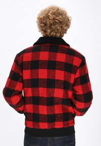 Rot-schwarz kariertes Jackett aus strukturiertem Stoff, mit schwarzem Kragen und taillierter Taille, von hinten gezeigt.