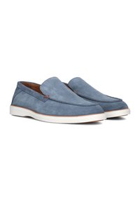Blauwe suède instapschoenen met een gladde textuur, ronde neus en witte rubberen zolen met subtiele rode accenten aan de zijkant.