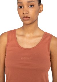 Rustfarvet ribbet tanktop med rund halsudskæring og broderet logo på brystet. Lavet af blødt bomuldsstof.