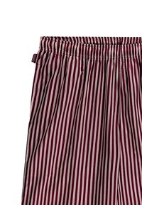 Randiga byxor med en bred elastisk midja, med alternerande mörkröda och krämfärgade vertikala ränder på ett slätt tyg.