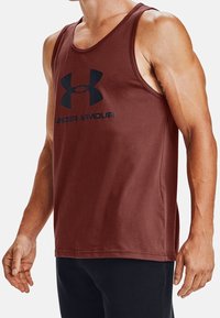 Bordowy top na ramiączkach wykonany z bawełny. Posiada okrągły dekolt oraz szwy boczne. Na piersi widnieje czarny logo Under Armour.