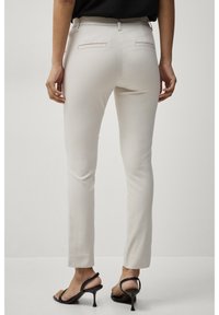 Béžové kalhoty na míru se slim fit, s mírně zvýšeným pasem, zadními kapsami a hladkou, lehkou texturou. 