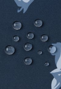 Blauer Stoff mit strukturierter Oberfläche, auf dem mehrere klare Wassertropfen sichtbar sind, die die wasserabweisenden Eigenschaften des Gewebes hervorheben.