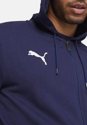 Marineblauwe zip-up hoodie met voorzakken, capuchon met trekkoord en wit Puma-logo op de linkerborst. Zachte stof met een aansluitend ontwerp.