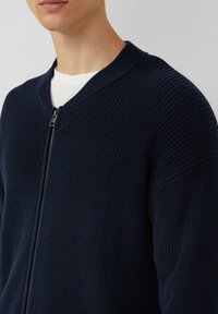 Marineblauer Strickpullover mit Reißverschluss, geripptem Muster und rundem Kragen. Verfügt über einen Frontreißverschluss und eine lockere Passform.