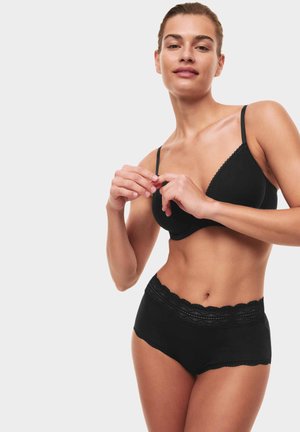 Zwarte bralette en hooggeknipte briefset gemaakt van zachte stof, met een golvende kantafwerking op de tailleband en de halslijn.