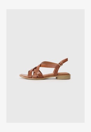 Sandale en cuir marron avec des bandes entrecroisées et une sangle arrière. Caractérisée par un petit talon carré et une semelle plate, elle présente un design simple.