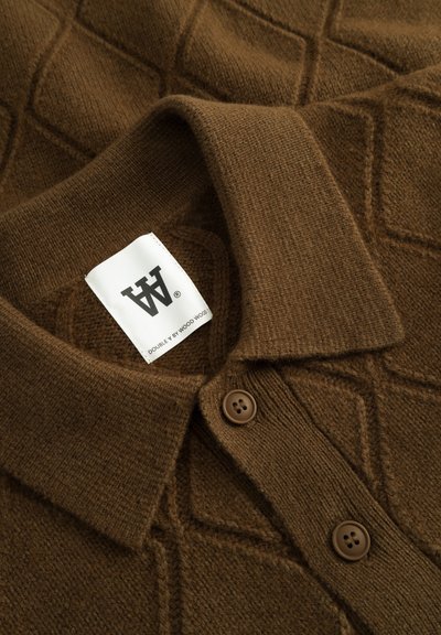 Polo en maille marron avec un motif en losange, devant boutonné et une étiquette affichant un logo. Tissu texturé et doux, avec un col classique.