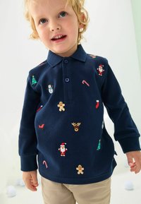Polo a maniche lunghe di colore blu navale con motivi natalizi ricamati che includono alberi, pupazzi di neve, bastoncini di zucchero e Babbo Natale in vari colori.