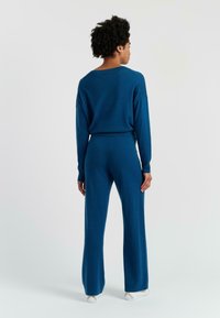 Blaues Strick-Loungewear-Set mit einem lockeren Pullover und weit geschnittenen Hosen. Strukturierter Stoff und gerippte Akzente erhöhen den Komfort und das Aussehen.