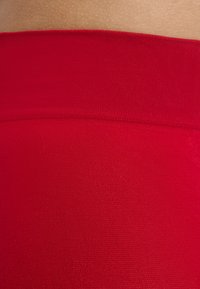 Cinturilla roja sin costuras de una prenda ajustada, textura suave, con un patrón de tela constante y sin hardware ni decoraciones visibles.