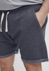 Grå bomullsblandingsshorts med tekstur, justerbar snøring i midjen, sidelommer og kontrasterende mørk grå oppbrett.
