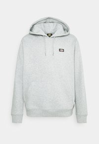 Felpa grigia realizzata in morbido tessuto testurizzato. Caratterizzata da una tasca frontale, cappuccio con cordoncino e un piccolo patch con logo sul petto.