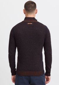 Sweter dziewiarski w ciemnym granacie z pomarańczowymi akcentami. Posiada wysoki kołnierz oraz ściągacze przy mankietach i u dołu. Skórzana metka z tyłu przy dekolcie.