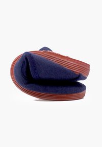 Scarpa in tessuto blu navy con un design flessibile e arrotondato e una suola in gomma marrone texturizzata, che presenta una struttura morbida e pieghevole.