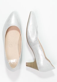 Chaussures à talons hauts argentées avec un design à bout pointu, texture métallique et accent en bois sur le talon. À l'intérieur, une semelle lisse de couleur beige.