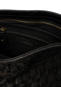 Borsa in pelle nera intrecciata con apertura superiore che rivela una tasca con zip interna e un'etichetta cucita all'interno.