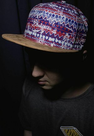 Cappello con un visiera in sughero testurizzato e una corona in tessuto a fantasia nei colori rosso, bianco e blu. Presenta la scritta "Blackskies" ricamata in bianco.
