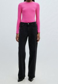 Haut ajusté rose à manches longues côtelées, associé à un jean large noir taille haute, équipé de poches avant et d'une fermeture à bouton argenté.