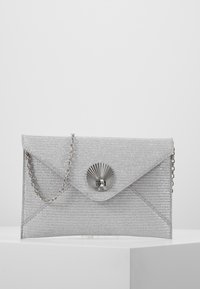 Srebrna torebka w stylu kopertówki o teksturowanej powierzchni, metaliczne zapięcie z motywem promieni słonecznych i łańcuszek na ramię.