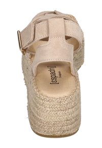 Beige espadrille platform sandal with a woven rope sole, suede upper, adjustable strap, and a flat footbed featuring logo detail.