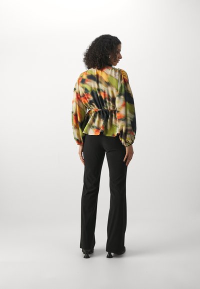 Bluză multicolor cu peplum, cu mâneci bufante, având un talie strânsă; asortată cu pantaloni negri evazați și toc.