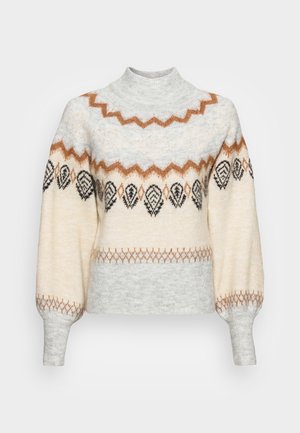 Pull tricot crème et gris clair à col montant, avec motifs marron en zigzag et feuilles noires sur la poitrine et les manches.