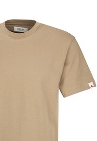 Beige katoenen T-shirt met een ronde hals en korte mouwen. Voorzien van een klein logoplaatje op de linker mouw. Gladde textuur, casual ontwerp.
