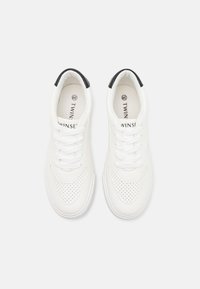 Hvite sneakers med svart hældetalj, perforert design på sidene, flate lisser og merket innersåle som viser "TWINSET."