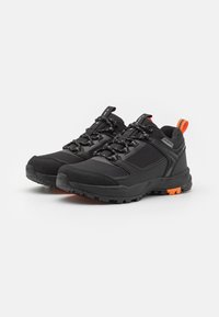 Sorte sportsko med et robust design, teksturert stoff, forsterket tå, og oransje detaljer på hælen og sålen for synlighet.