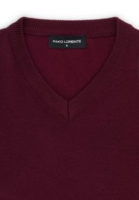 Burgundowy sweter w serek wykonany z miękkiej dzianiny. Posiada prążkowane wykończenie przy dekolcie oraz metkę z napisem "PAKO LORENTE" i rozmiarem "M".