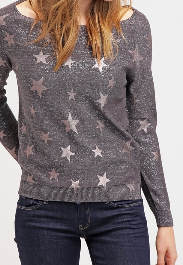 Grå stickad tröja med utskärningar vid axlarna, metallisk stjärnpryddning i mjuk rosa, långa ärmar och ribbat fåll. Kombinerad med mörk denim.