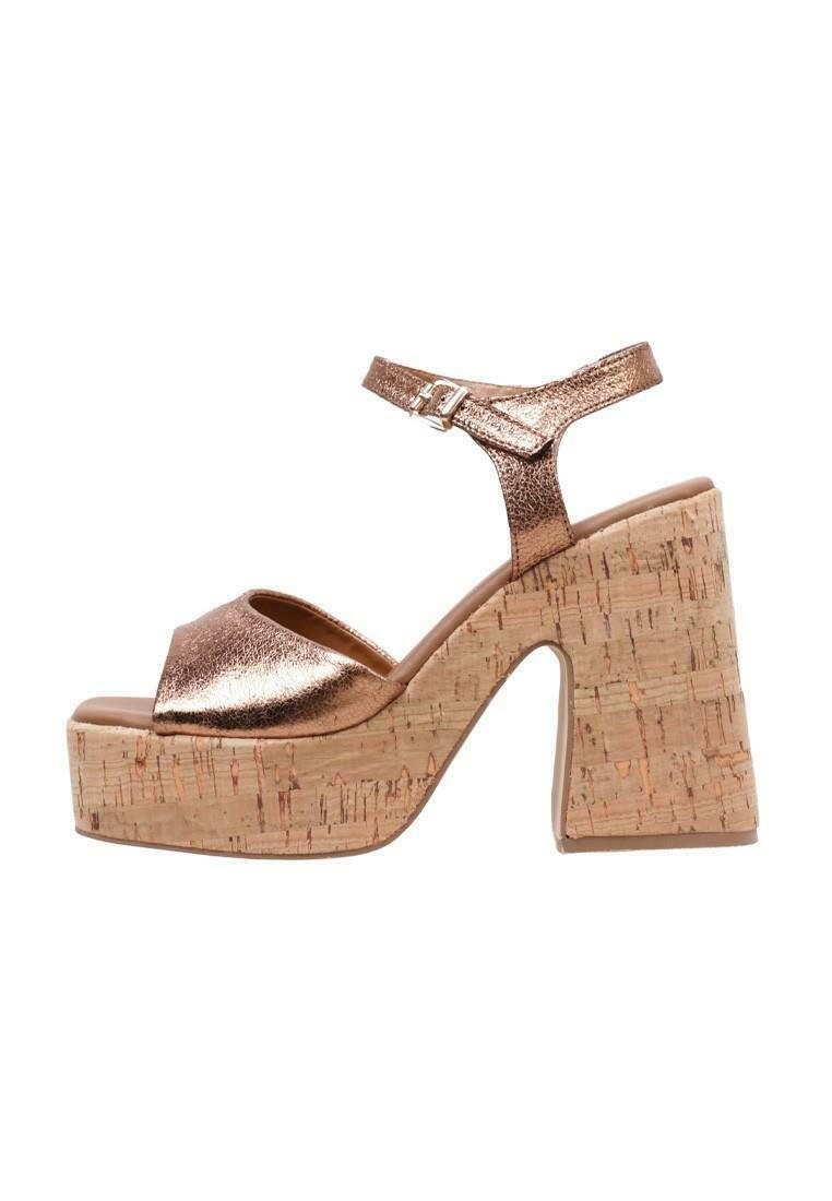Sandalias de plataforma metálicas en bronce con tacón de corcho. Presentan una correa ajustable en el tobillo y un diseño de punta abierta. Superficie superior texturizada.