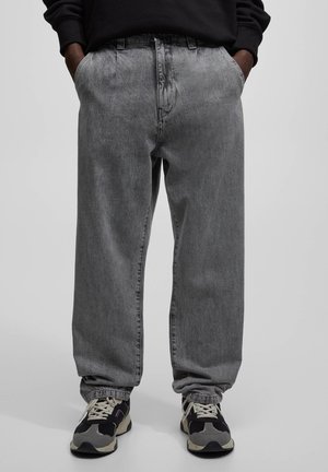 Grijze denim broek met een losse pasvorm, voorzien van een hoge taille, zijzakken en subtiele vervaging. Gepaard met zwart/grijze sneakers.